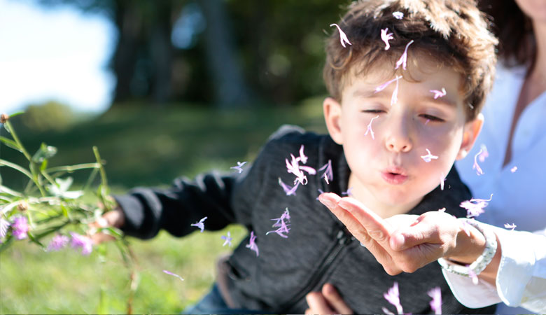enfant soufflant sur une fleur